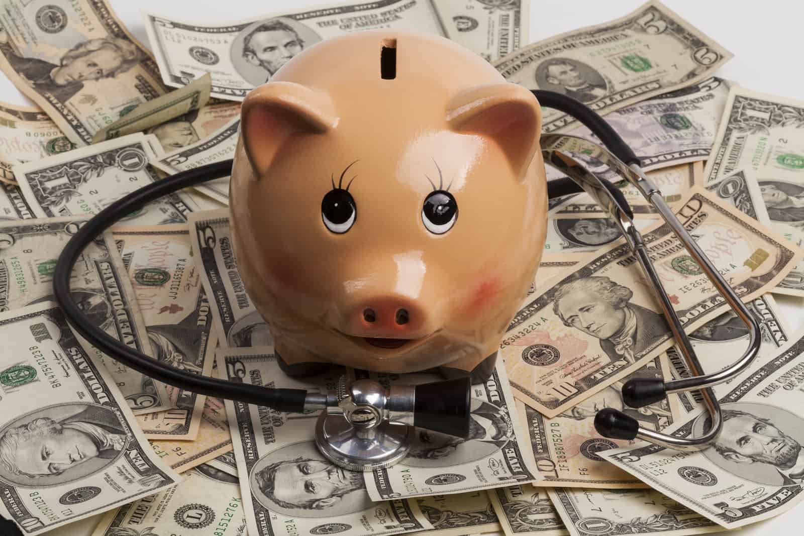 stethoscope with money and a piggy bank representing assessing financial health