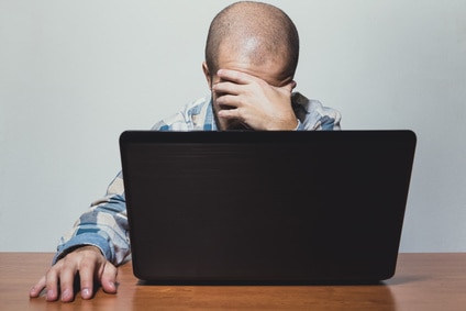 man looking at computer screen distraught because he can't retire yet